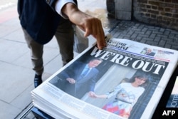 A man takes a copy of the London Evening Standard with the front page reporting the resignation of British Prime Minister David Cameron and the vote to leave the EU in a referendum on June 24, 2016.