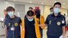 Petugas polisi dari Biro Investigasi Taiwan menggiring dua orang tersangka yang dideportasi dari Bangkok, ketika tiba di Bandara Internasional Taoyuan, Taiwan, pada 18 Agustus 2022. Keduanya diduga terlibat penipuan di Kamboja. (Taiwan Criminal Investigation Bureau via AP)