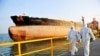 This photo taken on Nov. 16, 2020 shows Chinese immigration inspection officers in protective suits walking past an oil tanker ship at the port in Qingdao, in China's eastern Shandong province. 