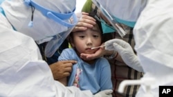 A child reacts to a throat swab during mass testing for COVID-19 in Wuhan