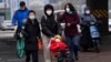 A child wearing a mask is pushed across a road in Beijing, Dec. 2, 2022. 