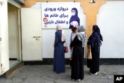 FILE - Afghan women stand outside an amusement park, in Kabul, Nov. 10, 2022. The Taliban have banned women from using gyms and parks in Afghanistan, part of their crackdown on women's rights and freedoms.