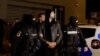 Andrew Tate dan Tristan Tate dikawal polisi di luar markas Direktorat Investigasi Kejahatan Terorganisir dan Terorisme di Bucharest (DIICOT) setelah ditahan selama 24 jam, di Bucharest, Rumania, 29 Desember 2022.
