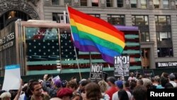A rainbow flag flies as people protest U.S. President Donald Trump's announcement that he plans to reinstate a ban on transgender individuals from serving in any capacity in the U.S. military, in Times Square, in New York City, New York, July 26, 2017. 