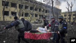 FILE - Rescuers and volunteers carry an injured woman from a maternity hospital that was damaged by shells in Mariupol, Ukraine, March 9, 2022. (AP Photo/Evgeniy Maloletka, File)