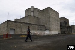 Seorang penjaga keamanan berjalan di depan gerbang utama Pembangkit Listrik Tenaga Nuklir Bataan di kota Morong di Provinsi Bataan, utara Manila. (Foto: AFP)