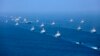 Liaoning aircraft carrier is accompanied by navy frigates and submarines conducting an exercises in the South China Sea. 