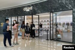 Orang-orang yang memakai masker berbaris di luar toko merek mewah Prancis Celine, di pusat perbelanjaan yang dibuka kembali di tengah wabah COVID-19 di Shanghai, China, 29 Mei 2022. (Foto: REUTERS/Brenda Goh)
