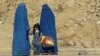 FILE - Afghan women clad in burkas wait for transportation on a road in Kabul, Nov. 5, 2012.