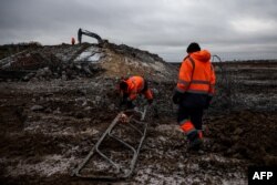 Pekerja memperbaiki jembatan yang hancur, diledakkan oleh pasukan Rusia saat mundur dari wilayah Kherson pada 6 Desember 2022. (ANATOLII STEPANOV / AFP)