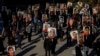 FILE - People hold signs with images of the victims of the downed Ukraine International Airlines flight PS752, in Toronto, Canada, Jan. 8, 2021.
