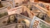 FILE - This picture taken Aug. 25, 2022, shows an Egyptian pound amid U.S. dollars. A worsening economy is choking households in Egypt.