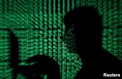 FILE PHOTO: A man holds a laptop computer as cyber code is projected on him in this illustration picture taken on May 13, 2017. (REUTERS/Kacper Pempel)