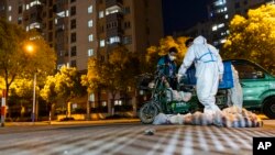 FILE - Deliverymen drop off food in Shanghai, China, April 11, 2022. A former judge posted on Dec. 10, 2022, that because Beijing has relaxed its zero-COVID policy, it is no longer appropriate to prosecute, convict and punish people for violating containment regulations.