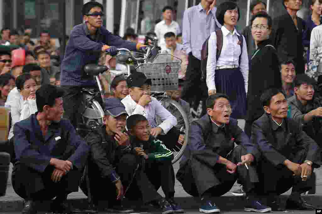 North Koreans react as they watch a movie shown on a giant screen in a public square near the Pyongyang train station.