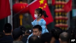 ARHIVA - Devojčica nosi masku dok je otac nosi na ramenima, u Pekingu, 7. oktobra 2022.