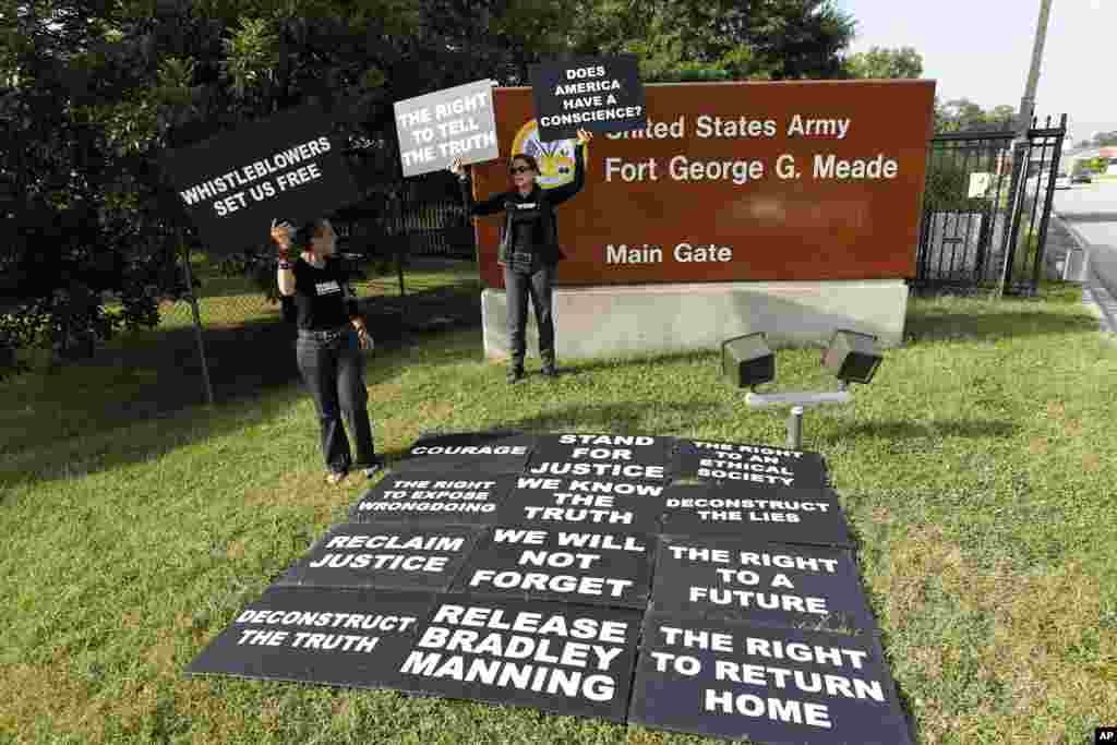 Para pendukung Prajurit Kelas Satu Bradley Manning menggelar dan memegang poster dalam sebuah protes di luar gerbang Fort Meade, Maryland (21/8). (AP/Jose Luis Magana)