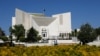 Police officers walk past the Supreme Court of Pakistan building, in Islamabad April 6, 2022, where a petition hearing to dissolve parliament by country's Prime Minister is taking place.