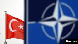Bendera Turki berkibar di sebelah logo NATO di markas Aliansi di Brussels, Belgia, 26 November 2019. (Foto: REUTERS/Francois Lenoir)