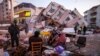Warga duduk dan berdiri di sekitar reruntuhan bangunan yang hancur akibat gempa di Golbasi, provinsi Adiyaman, selatan Turki, 8 Februari 2023. 