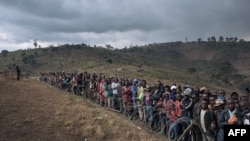 FILE - Displaced persons gather during a visit by the Congolese defense minister, not visible, to the internally displaced persons camp of Bijombo, South Kivu Province, eastern Democratic Republic of Congo, Oct. 10, 2020. 