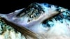 Na fotografiji snimljenoj sa NASA-ine sonde koja obleće Mars vide se tamne površine duge oko 100 metara na površini Marsa za koje naučnici veruju da ih uzrokuju potoci slane vode. (Foto: NASA)