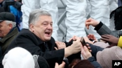 Ukrainian President Petro Poroshenko, left, greets people gathered to support an independent Ukrainian church near the St. Sophia Cathedral in Kiyv, Ukraine, Saturday, Dec. 15, 2018.