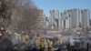 Petugas pemadam kebakaran dan petugas penyelamat membersihkan lokasi kebakaran di desa Guryong di Seoul, Korea Selatan, Jumat, 20 Januari 2023. (AP/Ahn Young-joon)