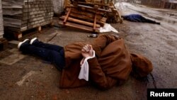 Тіло людини зі руками, зв’язаними білою тканиною. За словами мешканців, людину застрелили російські солдати та залишили на вулиці під час вторгнення Росії в Україну в Бучі, Україна, 3 квітня 2022 року. REUTERS