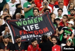 Para suporter Tim Sepakbola Iran memegang spanduk bertuliskan 'Kebebasan hidup perempuan' di dalam stadion selama pertandingan Tim Piala Dunia Grup B antara kesebelasan Iran melawan Inggris, di Stadion Internasional Khalifa, Doha, Qatar, 21 November 2022 REUTERS/Paul Childs