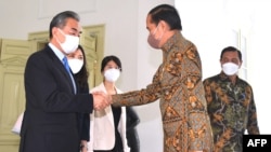 Presiden Indonesia Joko Widodo (kanan) berjabat tangan dengan Menteri Luar Negeri China Wang Yi (kiri) di Istana Merdeka di Jakarta pada 11 Juli 2022 lalu (foto: ilustrasi). 