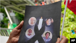 A Myanmar national living in Thailand holds the pictures of the executed political prisoners in Myanmar, as they protest outside Myanmar's embassy in Bangkok, Thailand, Tuesday, July 26, 2022. International outrage over Myanmar's execution of four politic