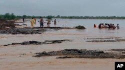 Rescue workers help villagers evacuate from flooded area caused by heavy rains, in the Pakistan district of Lasbela, July 26, 2022. A military helicopter supervising relief efforts went missing on Aug. 1, 2022.
