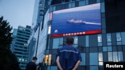 Seorang pria menyaksikan siaran berita CCTV tentang operasi militer yang dilakukan tentara China yang ditampilkan pada layar di salah satu pusat perbelanjaan di Beijing, pada 3 Agustus 2022. (Foto: Reuters/Thomas Peters)