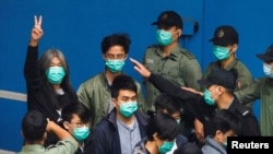 Aktivis pro-demokrasi Hong Kong, Leung Kwok-hung, memberi salam dua jari saat berjalan ke mobil lapas bersama para aktivis lainnya untuk menuju ke gedung pengadilan, di Hong Kong, China, 4 Maret 2021. (Foto: Stringer/Reuters)