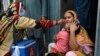 A health worker administers polio vaccine drops to a child during a door-to-door polio vaccination campaign at a slum area in Lahore, Pakistan, May 23, 2022. 