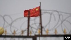 Bendera China berkibar di belakang kawat berduri di kompleks perumahan di wilayah Xinjiang barat China, 4 Juni 2019. (Foto: AFP)