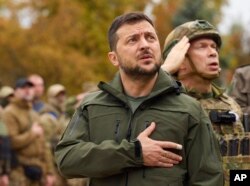In this photo provided by the Ukrainian Presidential Press Office, Ukrainian President Volodymyr Zelenskyy sings the Ukrainian national anthem during his visit to the city of Izium, Kharkiv region, Ukraine, Sept. 14, 2022.