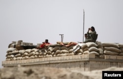 FILE - Fighters of the Syria Democratic Forces, an alliance of Kurdish, Arab, Assyrian, Armenian, Turkmen and Circassian fighters, take an overwatch position in northern province of Raqqa, Syria, May 27, 2016.