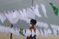 Članica organizacije Rio de Paz kači bele maramice koje simbolizuju oproštaj od žrtava Kovida 19, na plaži Kopakabana u Rio de Žaneiru, 8. oktobra 2021.