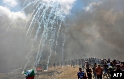 Palestinci trče u zaklon od suzavca koji su ispalile izraelske snage u blizini granice sa Pojasom Gaze, istočno od grada Gaze, 14. maja 2018.
