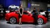 Model looks on as man cleans Jaguar at the 2013 Los Angeles Auto Show, Los Angeles, Nov. 21, 2013.