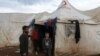 Ahmad Hamra, stands with his children outside a tent at an internally displaced Syrian camp, in northern Aleppo near the Syrian-Turkish border, Syria, Feb. 17, 2021. 
