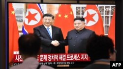 People watch a television news screen showing North Korean leader Kim Jong Un shaking hands with Chinese President Xi Jinping, at Seoul railway station in Seoul on June 20, 2019.