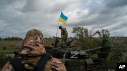 A Ukrainian national guard serviceman stands atop a destroyed Russian tank in an area near the border with Russia, in Kharkiv region, Ukraine, Sept. 19, 2022.
