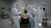 FILE - Medical workers in protective suits treat a patient (not the author of this story) infected with the coronavirus, at a makeshift hospital set up at the Sokolniki Exhibition and Convention Center in Moscow, Russia, Nov. 9, 2020. 