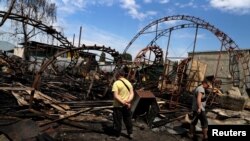 Workers inspect a damaged wood warehouse after a strike in the outskirts of Kharkiv, Ukraine, June 3, 2022.