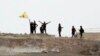 Fighters with the Kurdish People's Protection Units, or YPG, wave their yellow triangular flag on the outskirts of Tal Abyad, Syria, June 15, 2015.