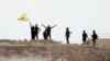 Fighters with the Kurdish People's Protection Units, or YPG, wave their yellow triangular flag on the outskirts of Tal Abyad, Syria, June 15, 2015.