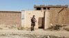 FILE - A Taliban fighter stands guard in front of a house adjacent to a suspected Islamic State hideout raided by Taliban forces, in northern Kabul, Afghanistan, Oct. 4, 2021.